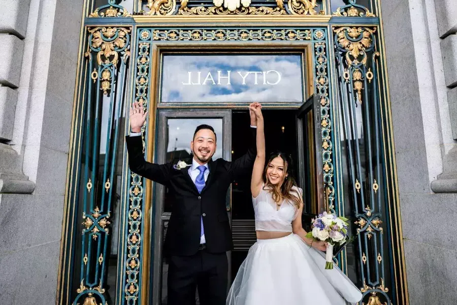 Couple posing in front of city hall after wedding